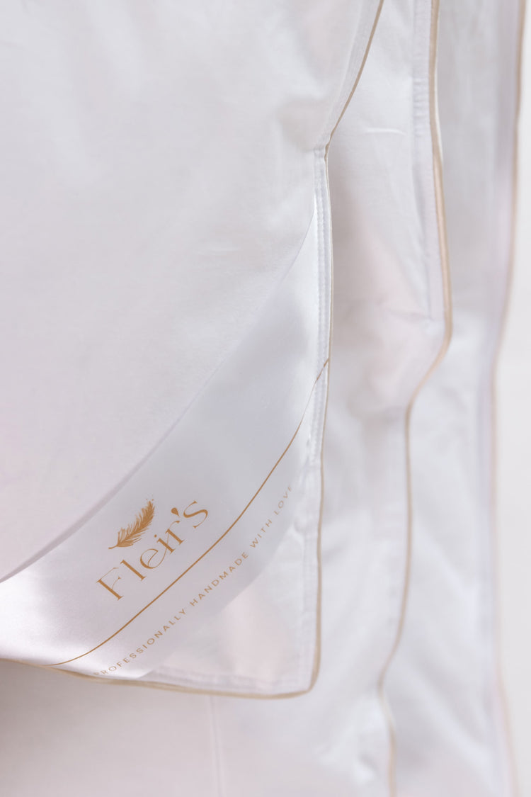 Close-up of Fleir`s luxury Hungarian goose down duvet with white cotton fabric, satin piping and Fleir`s branding